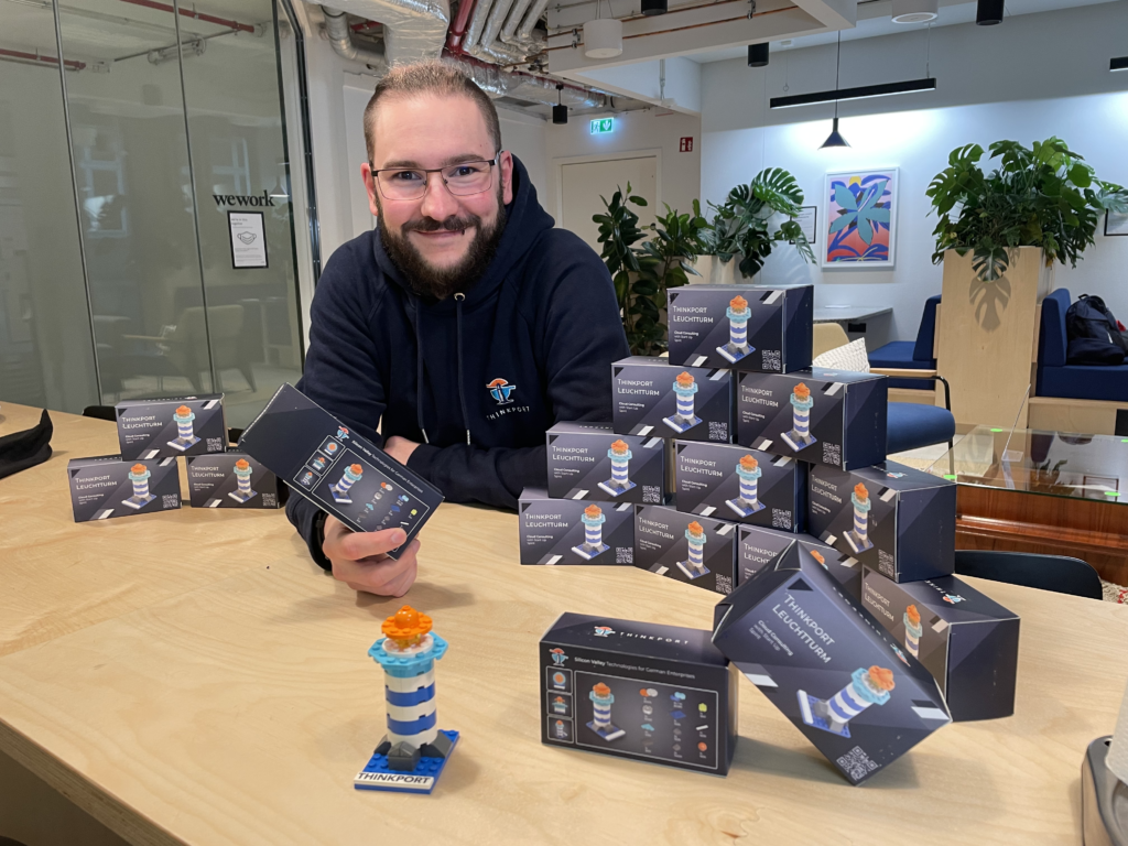 Entwickler Lars inmitten der von ihm entwickelten Thinkport Logo Leuchtturm Verpackungen