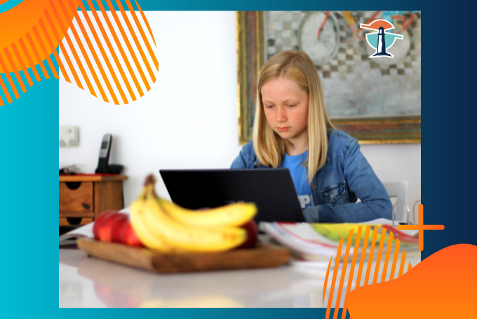 Ein Mädchen sitzt am Laptop. Davor liegen 2 Bananen und Äpfel sowie aufgeklappte Bücher.