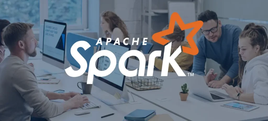 Im Vordergrund sieht man das Apache Spark Logo sowie Schriftzug, und im Hintergrund sitzen Personen am Schreibtisch vor dem Laptop und Monitoren.